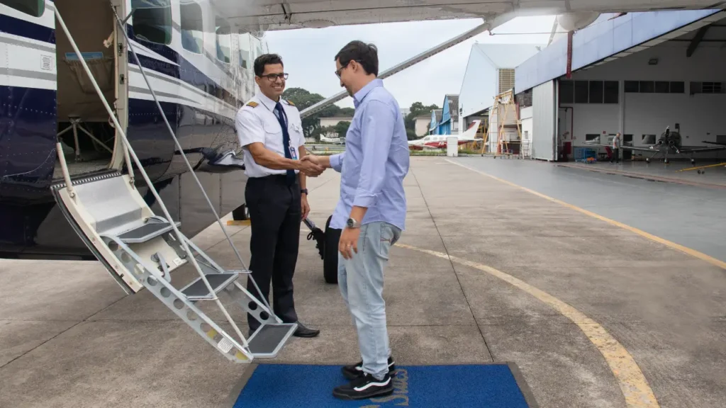 Hangar Campo de Marte: estrutura estratégica para a aviação executiva Dois homens se cumprimentando no hangar Campo de Marte ao lado de um avião